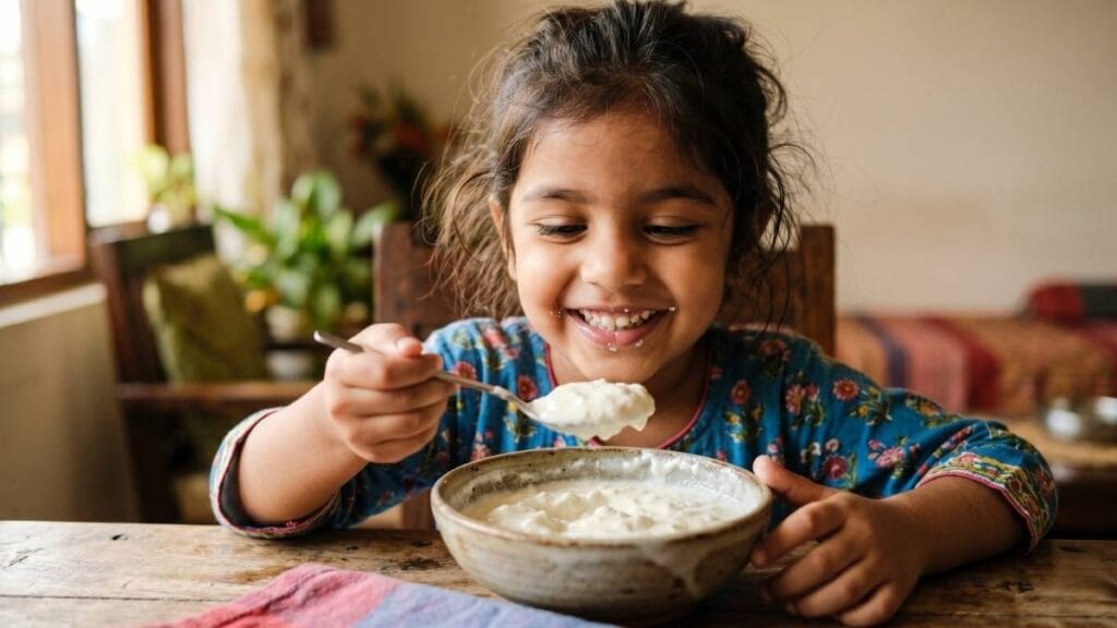 लहान मुलांची रोगप्रतिकारक शक्ती (Immunity) वाढवणे यात पचनसंस्थेचे महत्त्व - ताजे दही खाणारी मुलगी.
